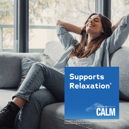 Woman relaxing on couch holding a Natural Vitality Calm product, conveying a sense of relaxation and tranquility.