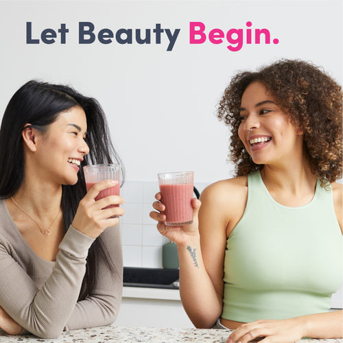 Two young women enjoying pink Collagen Complex smoothies while smiling.