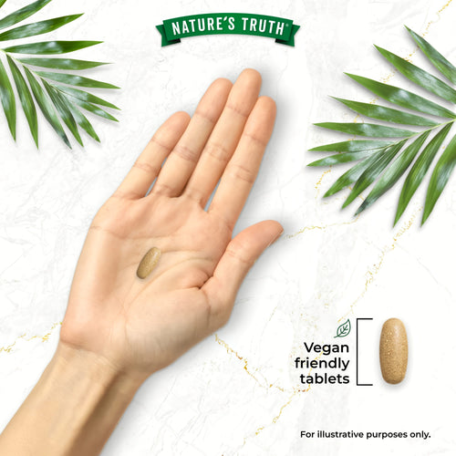 A hand holds a light brown Dandelion 500mg tablet. Another tablet lies beside text reading 'Vegan friendly tablets'.
