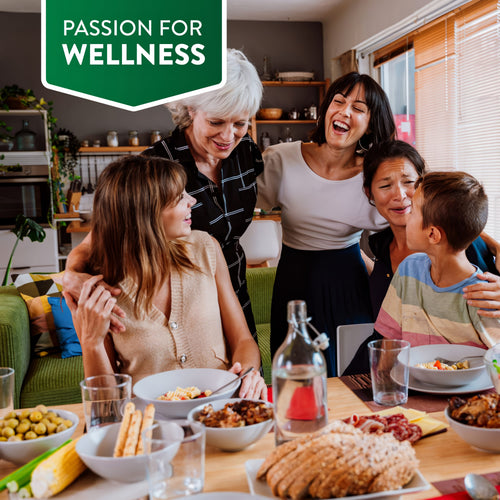 Adults and a child enjoy a meal together, laughing and hugging at the table.